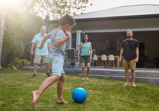 un groupe d'enfants et d'adultes en train de jouer au foot devant une maison