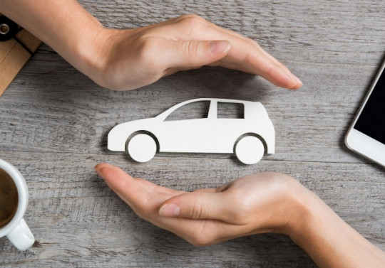 une voiture en papier en 2 mains