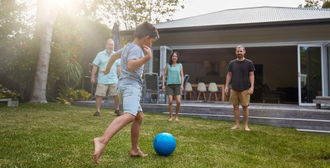 un groupe d'enfants et d'adultes en train de jouer au foot devant une maison