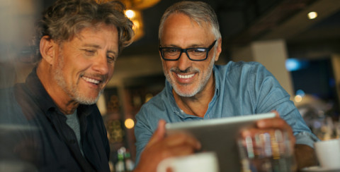 photo Article : deux amis sourient  et regardent un ipad