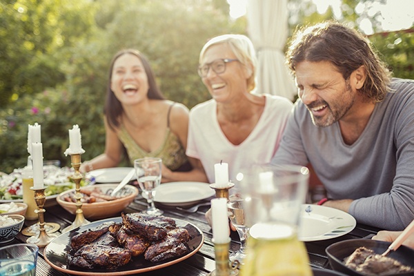 un groupe, 2 femmes, et un homme en train de rire pendant un repas